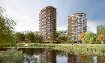 Twee flats in een groene omgeving met een sloot op de voorgrond en bomen aan de rechterzijde